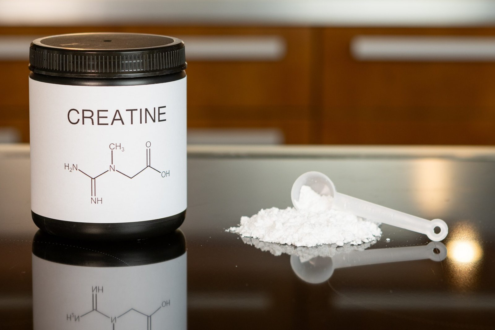 a bottle of creatine next to a spoon on a table